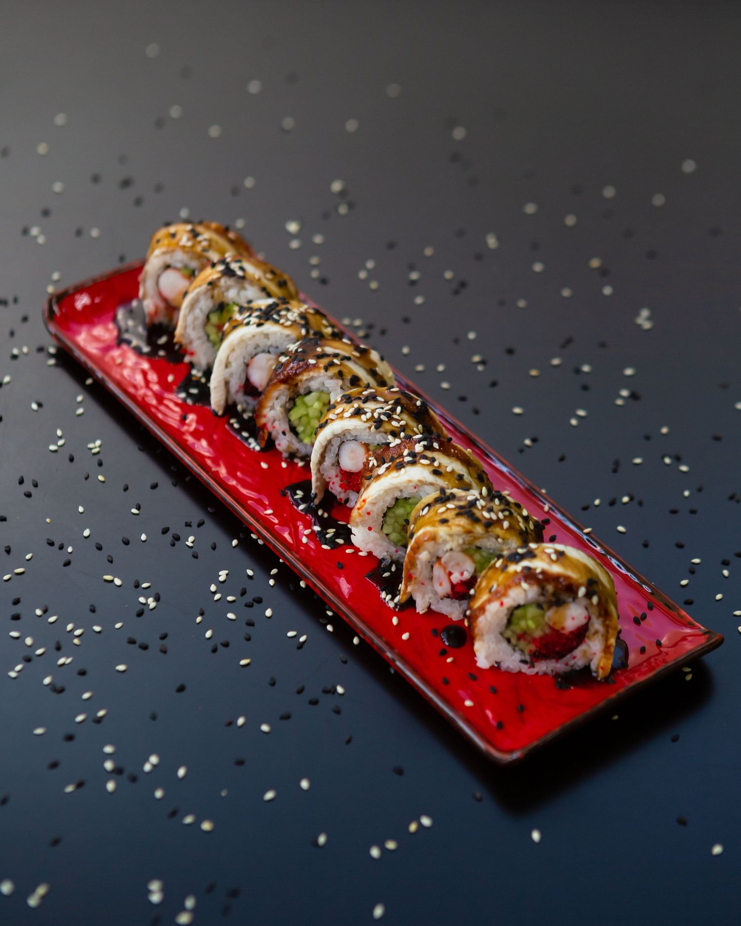 Artfully plated sushi roll with colorful toppings and garnishes served on a vibrant red platter.