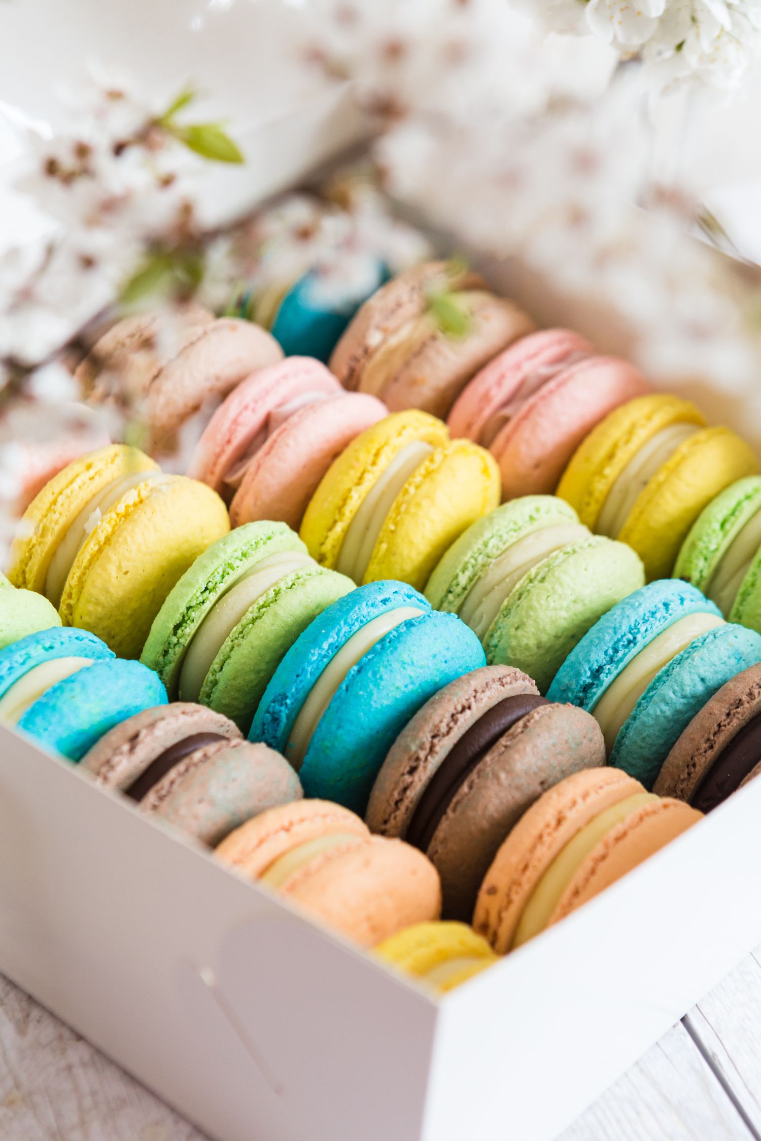 Box of assorted French macarons in vibrant colors arranged in neat rows.