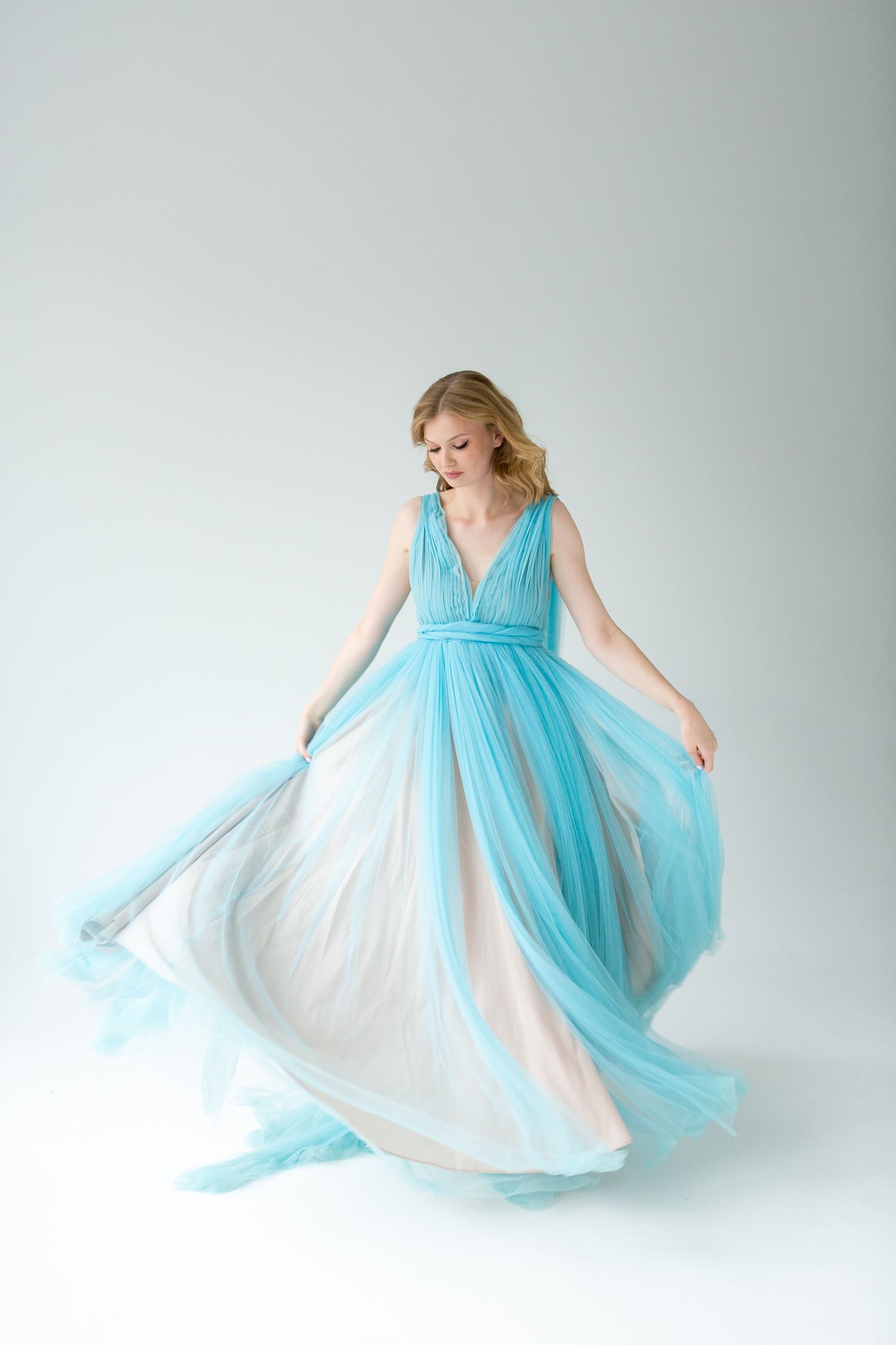 Ethereal fashion shot of flowing turquoise and white tulle gown in motion.