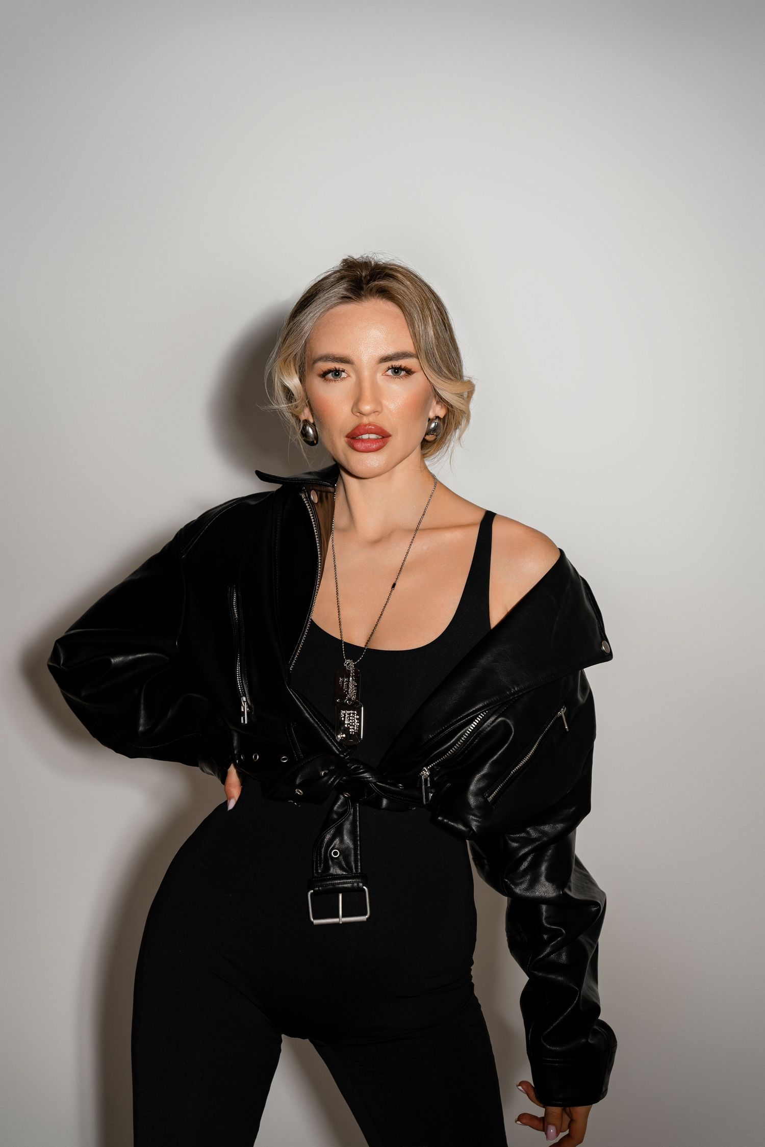 A model poses in black velvet outfits against a grey backdrop in an artistic fashion photography series.