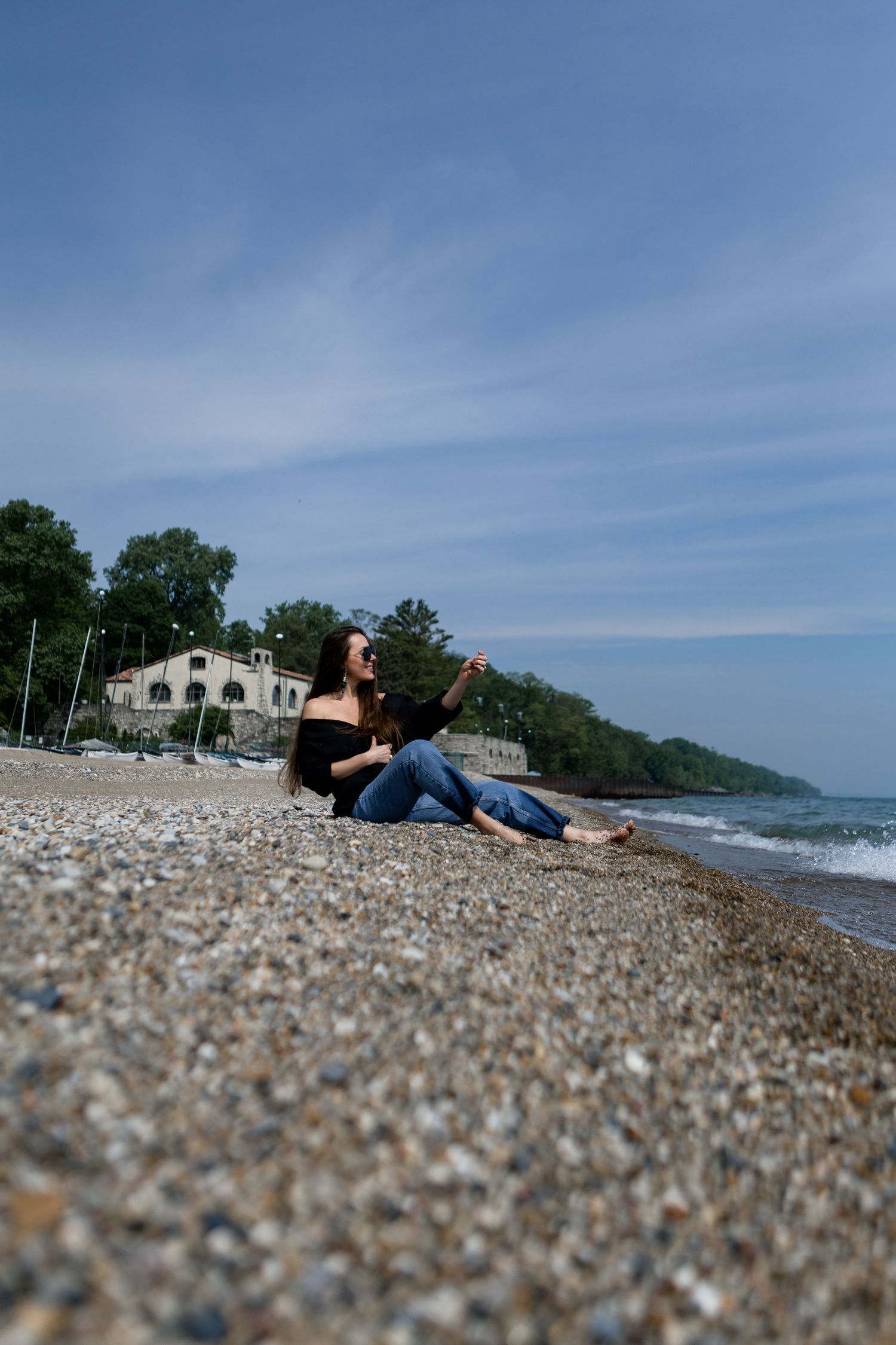 A rocky beach shoreline on a sunny day with blue skies and water stretching into the distance.