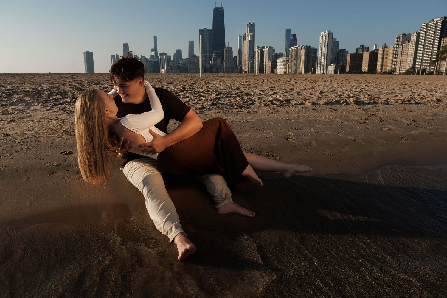 Chicago skyline reflects in Lake Michigan during golden hour as people enjoy sunset at North Avenue Beach.
