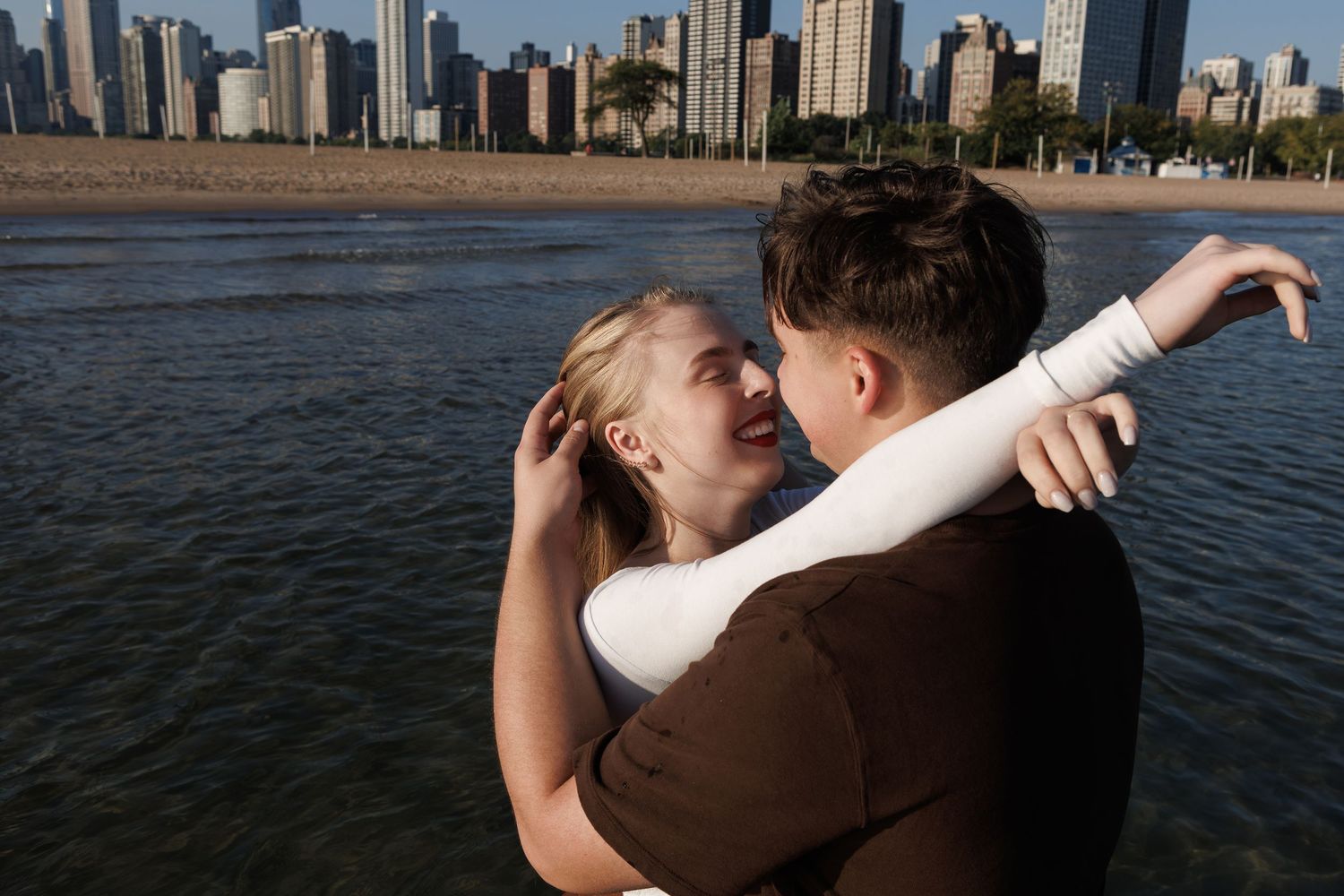 Romantic couple embraces while dancing along Chicago's waterfront with city skyline in background at sunset.
