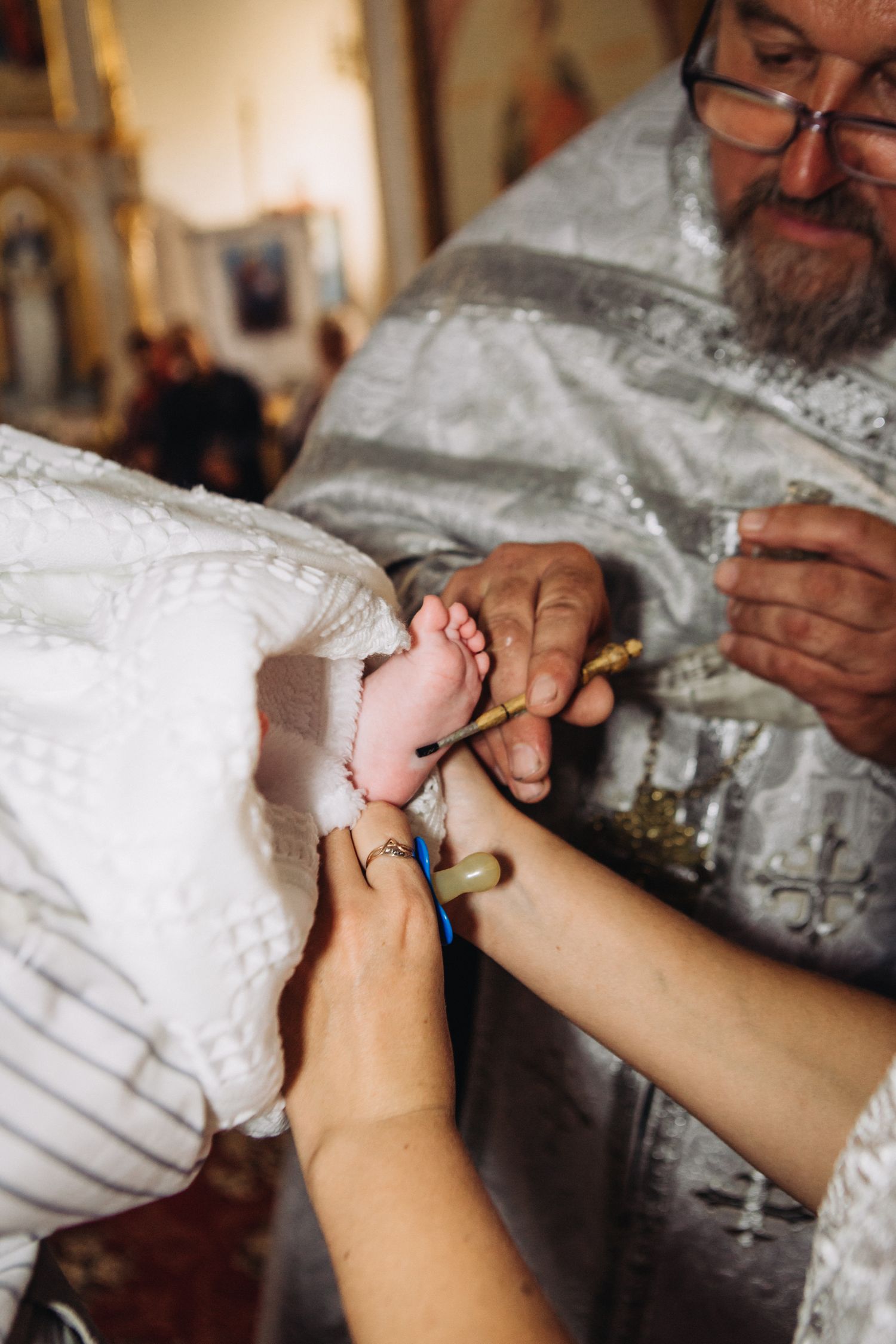 Close-up of tiny foot being held during religious baptism ceremony.