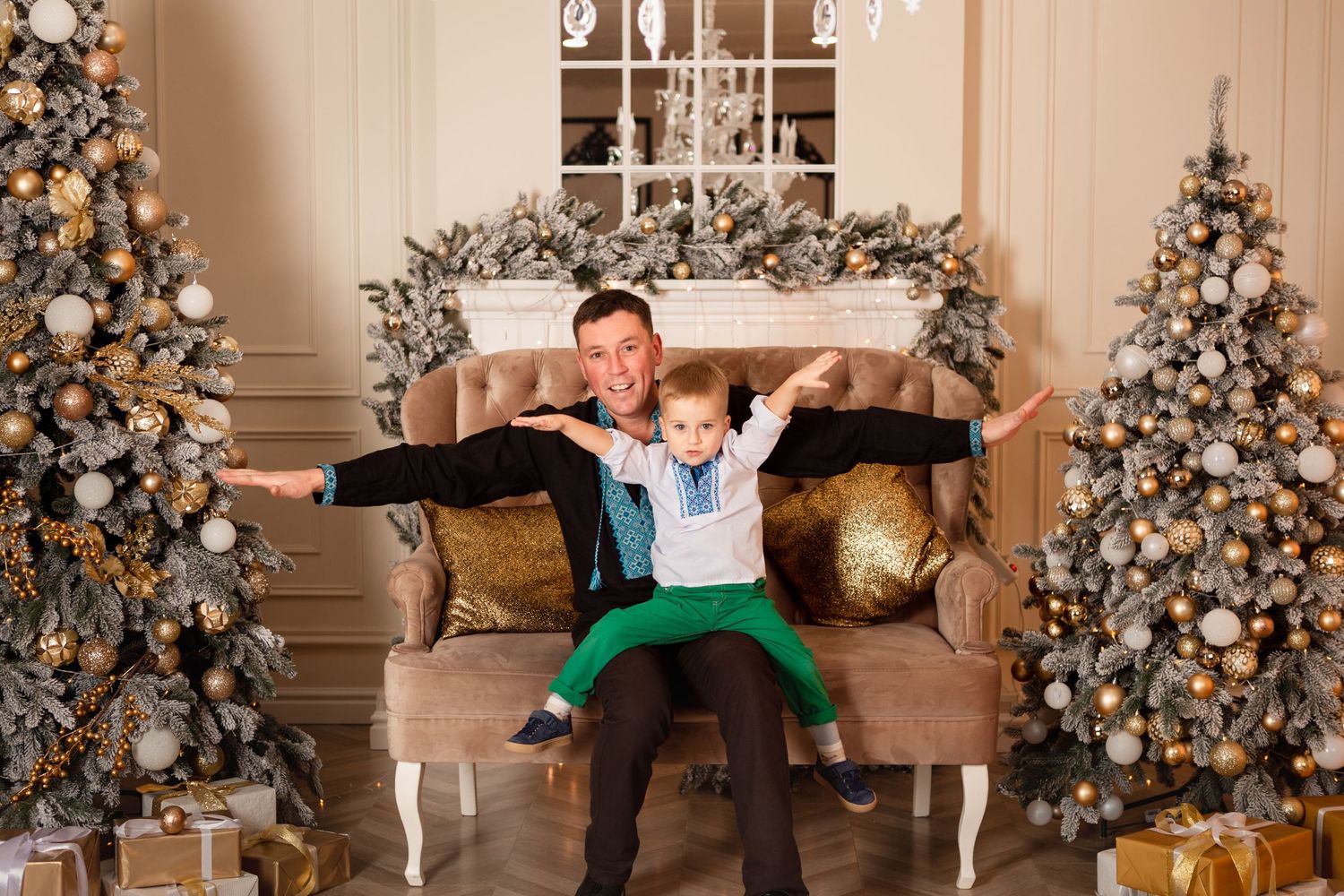 Playful moment captured on beige sofa between decorated Christmas trees.
