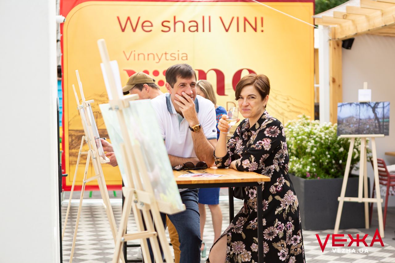 Outdoor wine tasting area with yellow banner and seating arrangements.
