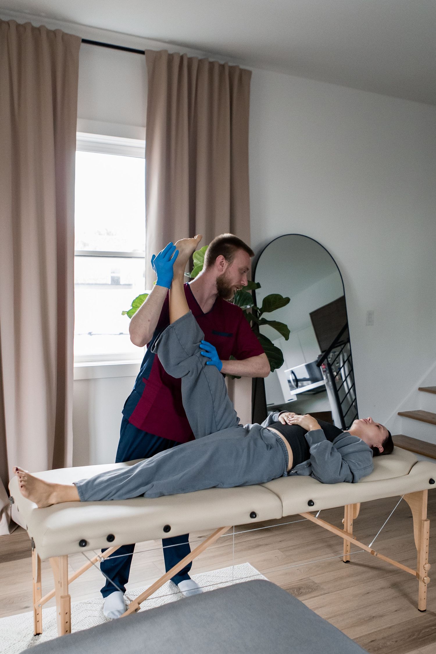 Physical therapist performing treatment on patient lying on massage table in modern clinic room.