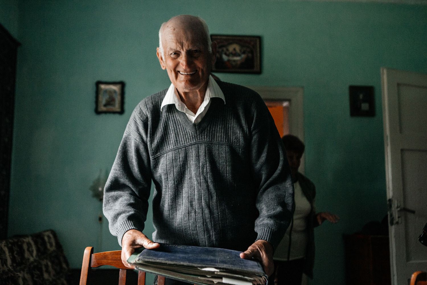 Senior person standing in room with green walls and vintage furnishings.