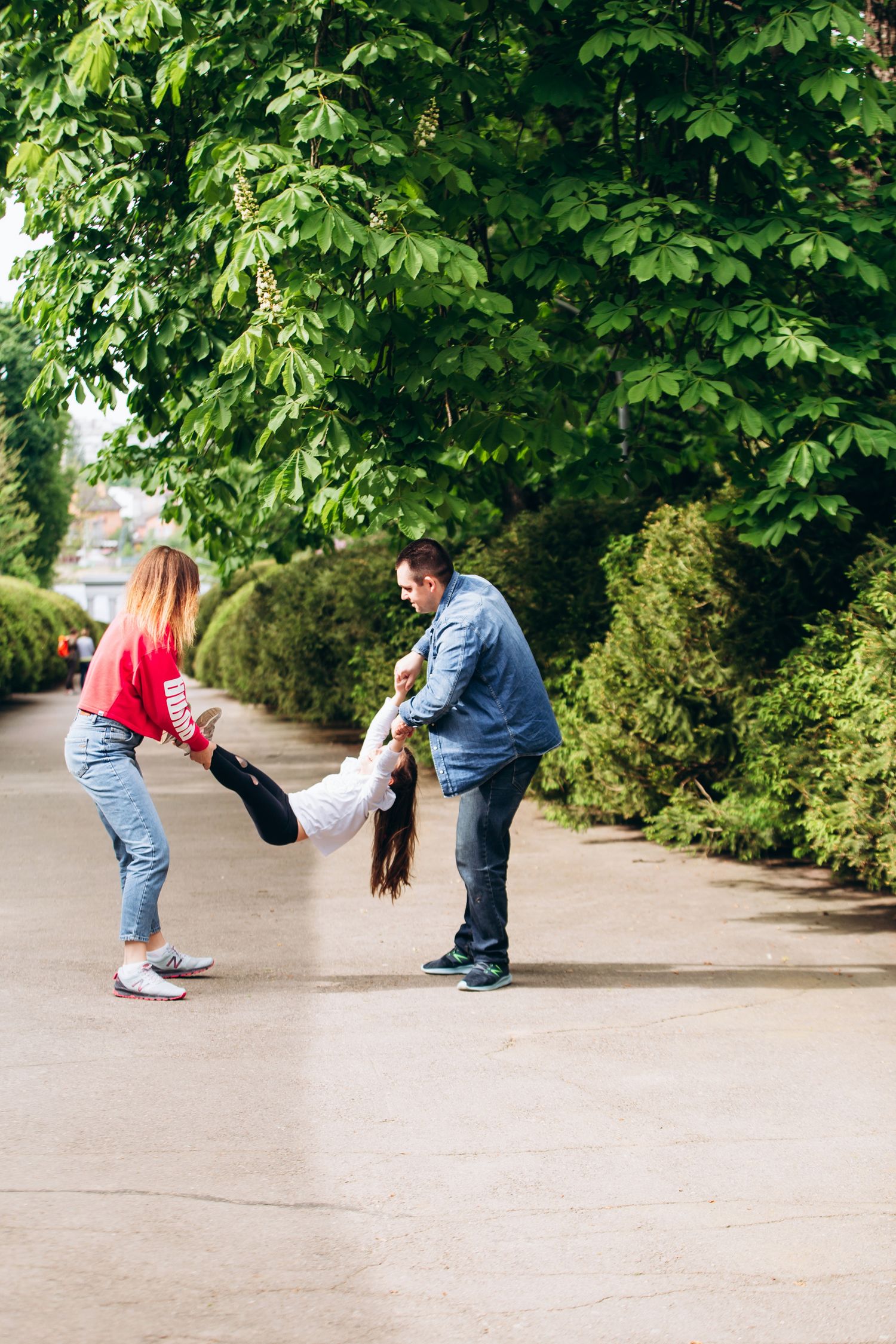 A joyful playtime moment on a pathway surrounded by green trees.
