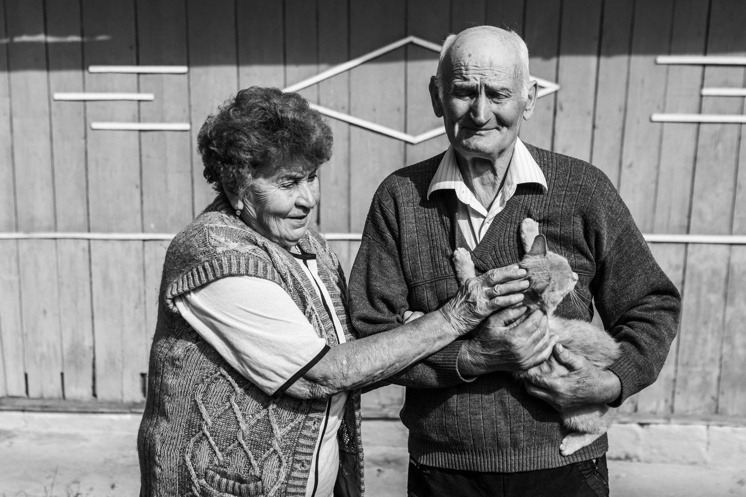 Black and white photo of a couple holding a small animal outdoors.