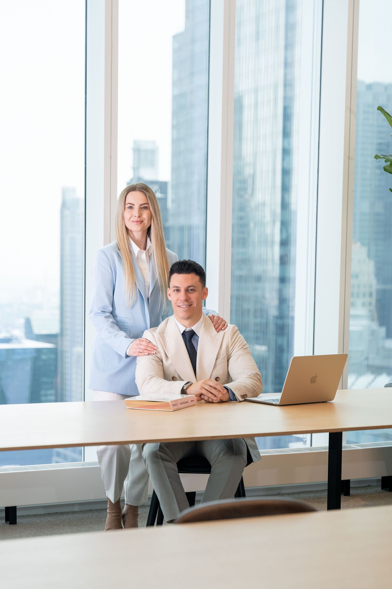 Business professionals working together at desk in modern office with city views.