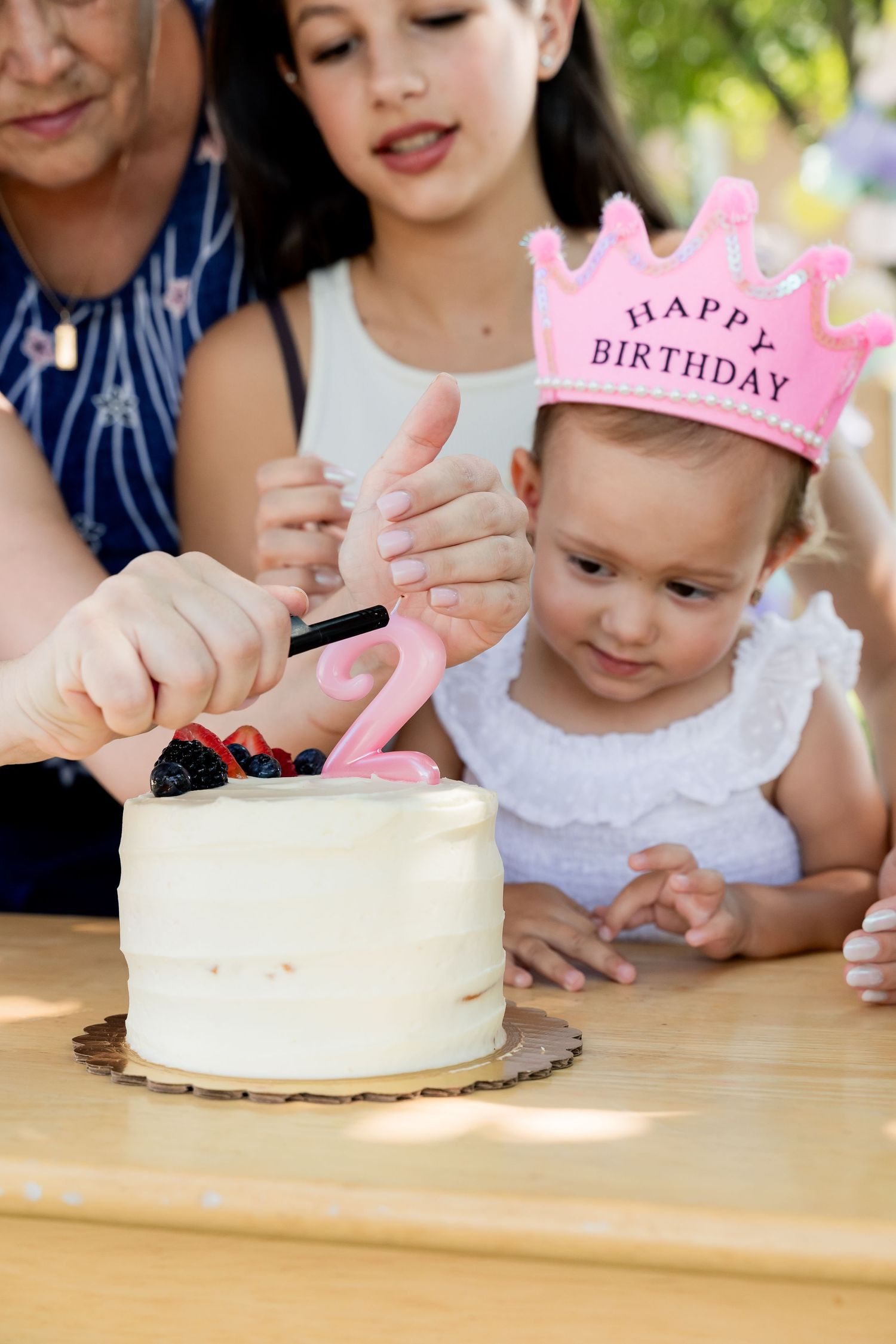 A birthday celebration with a white cake and pink crown as decorative elements.