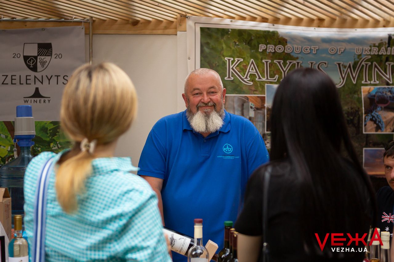 Wine tasting booth with wooden roof structure attended by staff member.