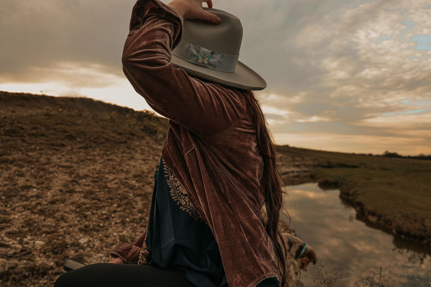 Woman holding her hat in a dark landscape
