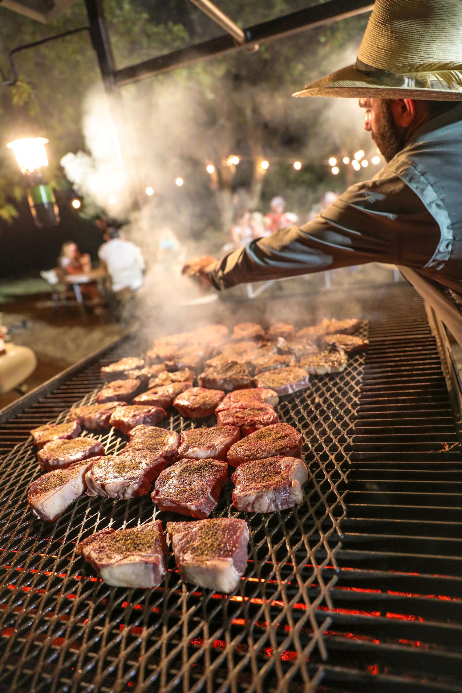 Man flipping steaks over a large fire