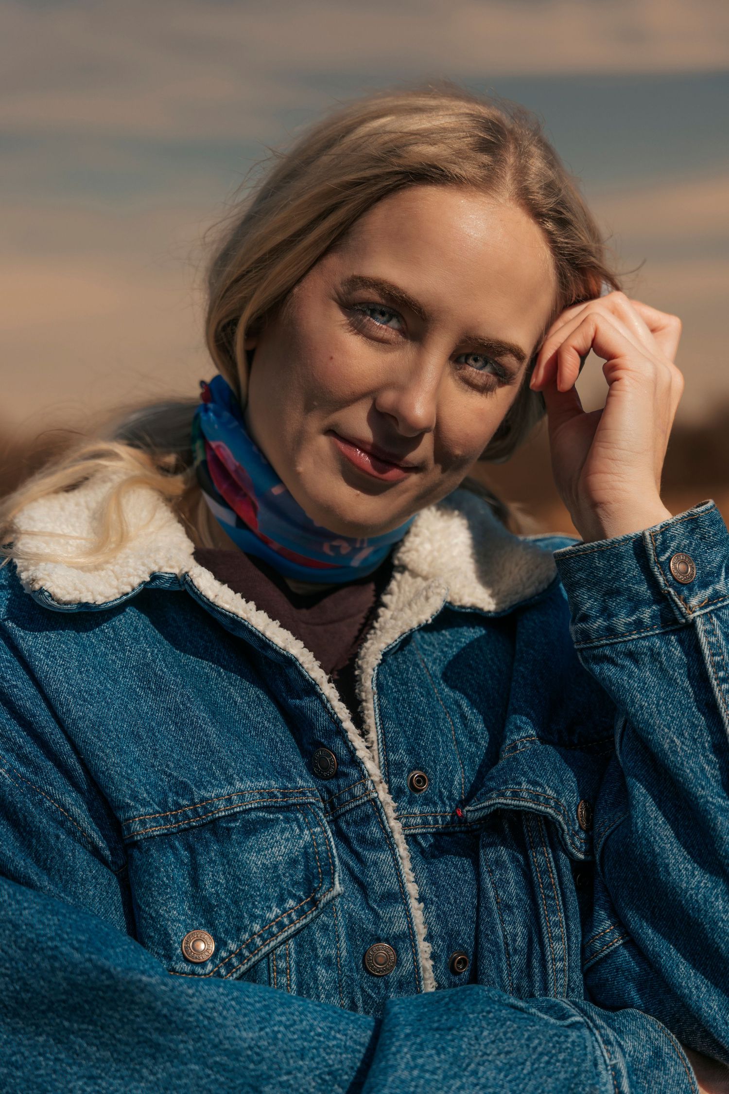 Woman holding her hand up to her face in a denim jacket