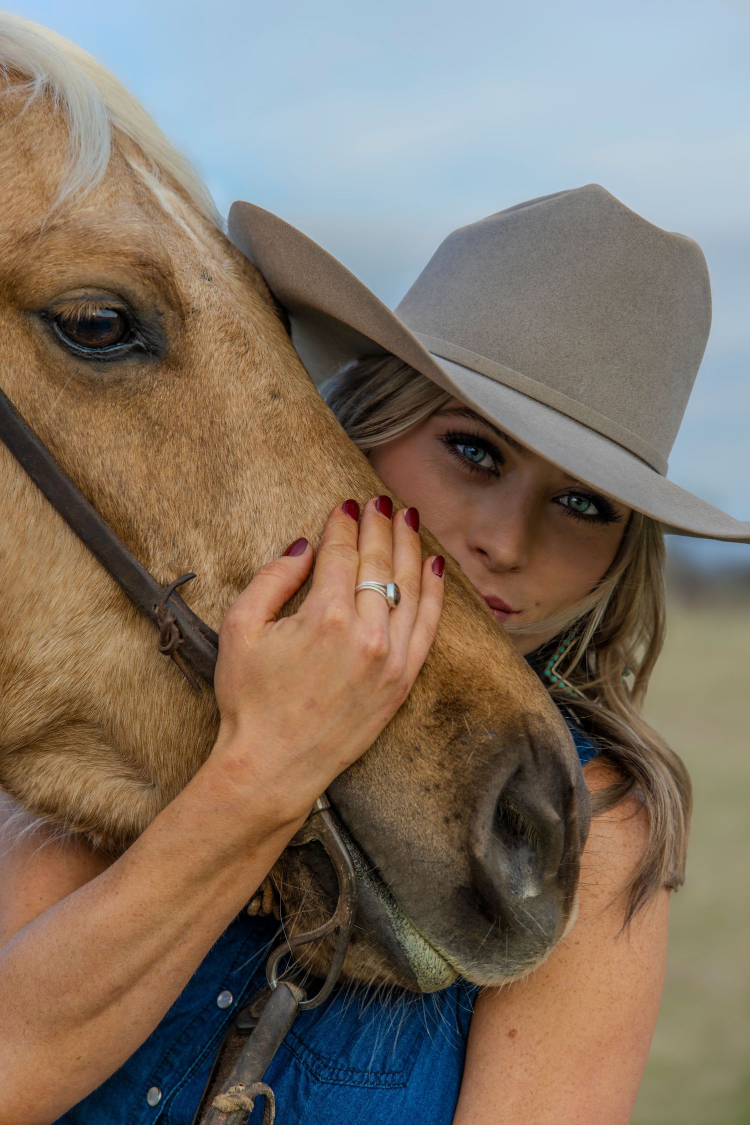 Woman holding the nose of a horse wearing a cowboy hat