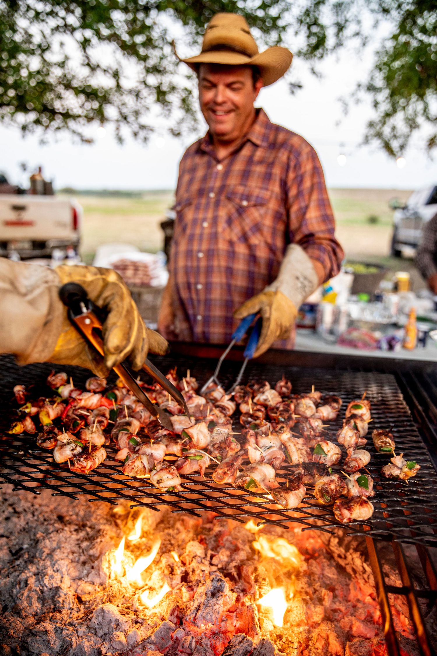 Man flipping steaks over a large fire