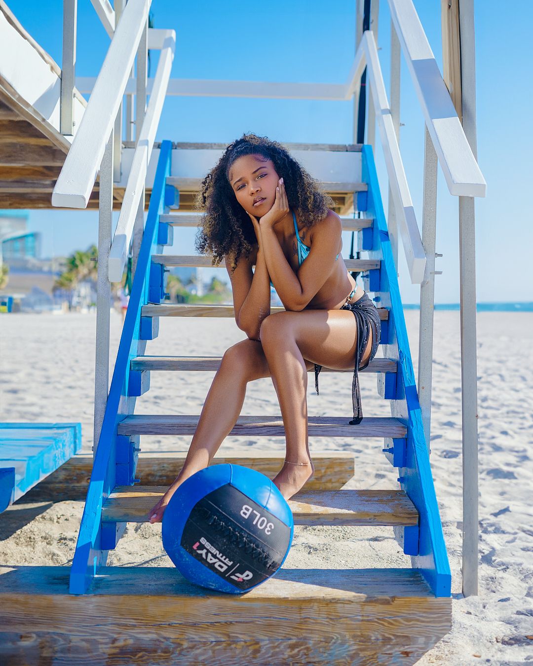 Fitness-inspired beach photoshoot featuring exercise ball and wooden steps.