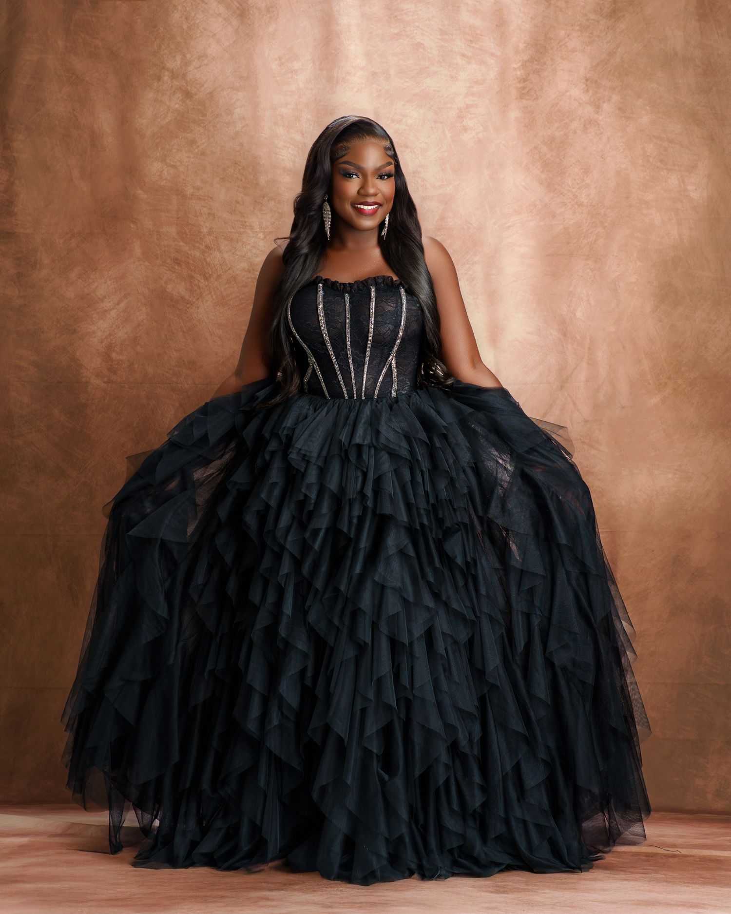 Luxurious black ballgown with voluminous ruffled tiers shown in studio portrait series.