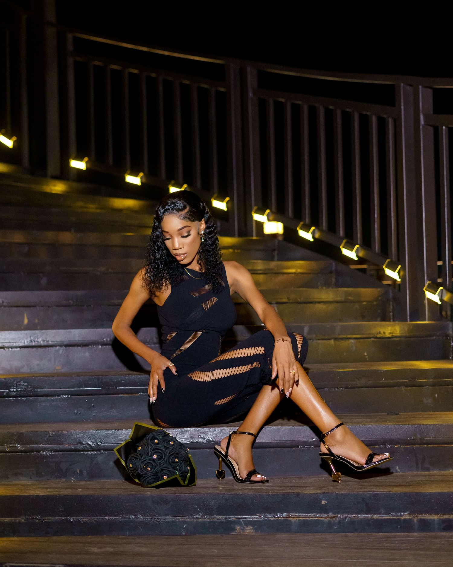 Fashion model poses dramatically on concrete steps in a navy cutout dress and heels.