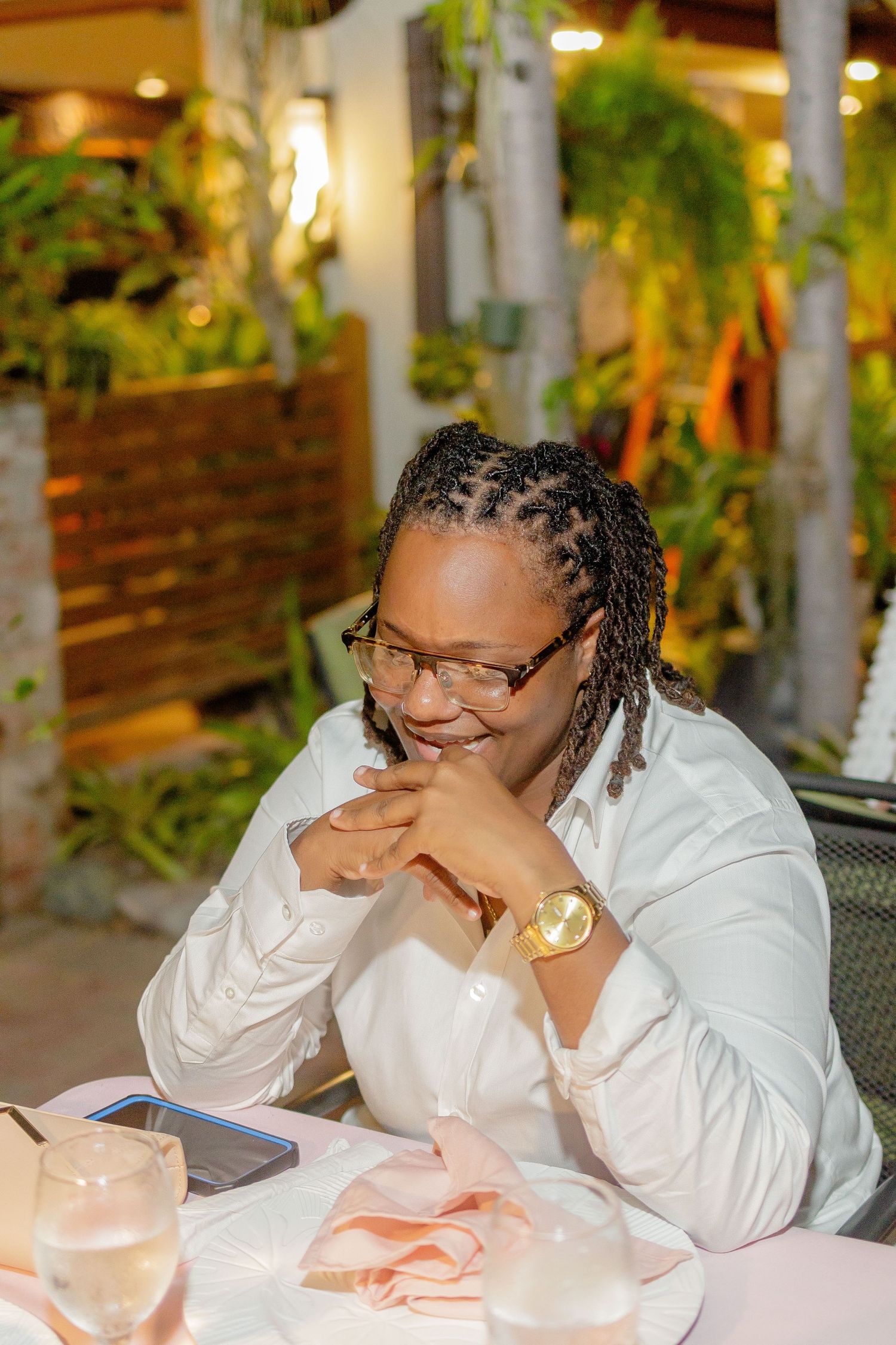 A person in white attire resting their head while sitting at a dining table.