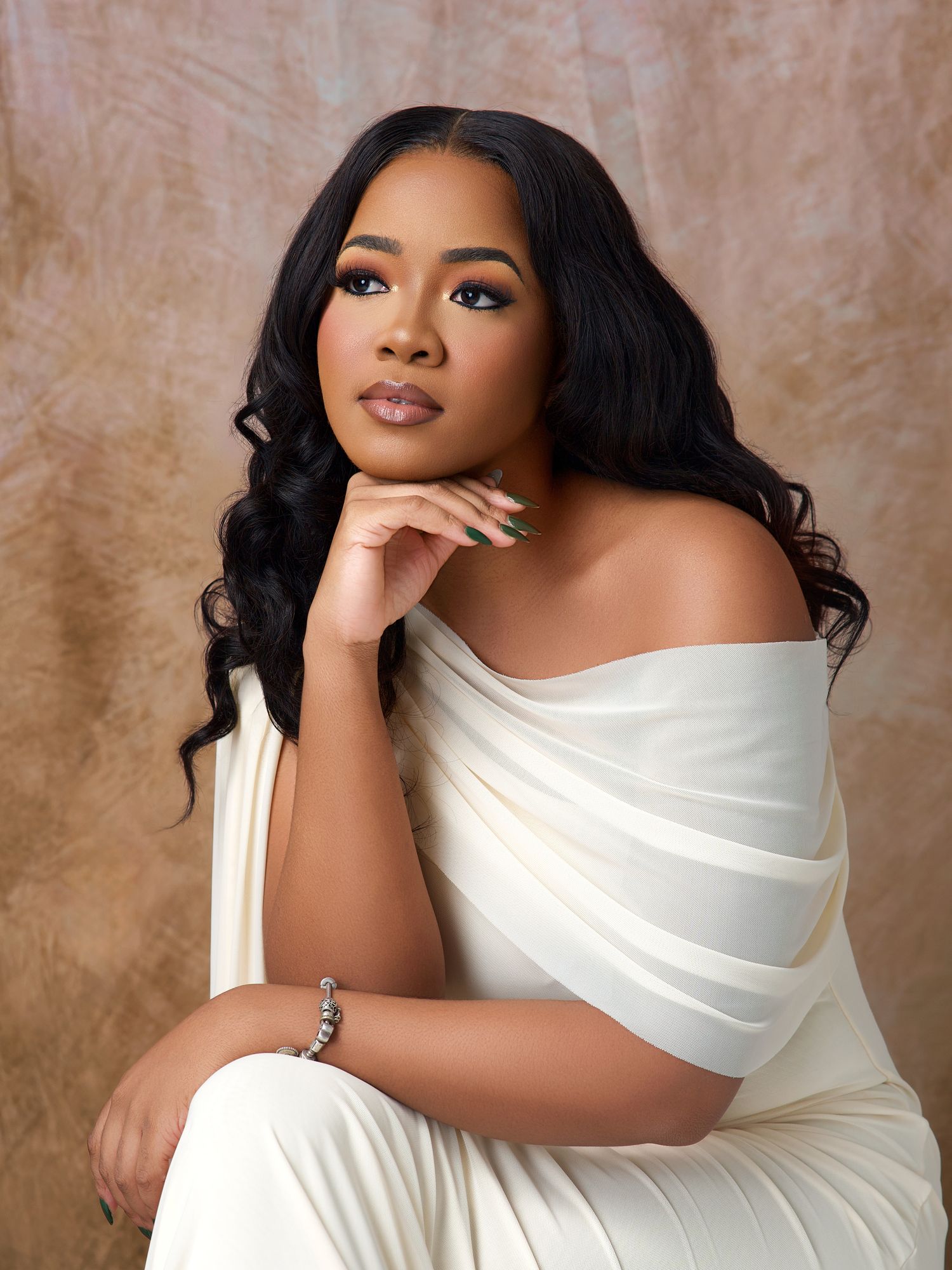 Artistic portrait session featuring white off-shoulder dress against warm brown background.