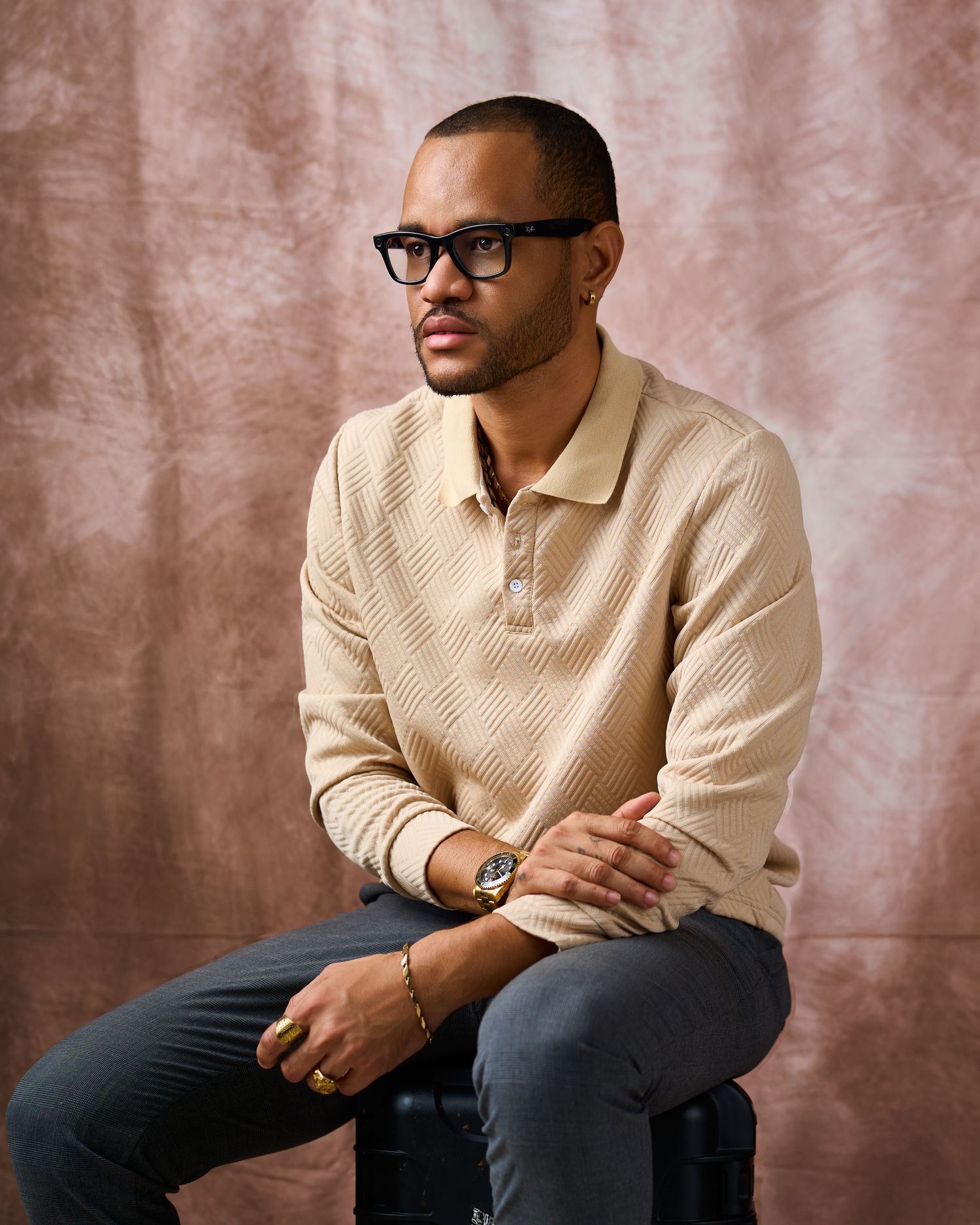 Casual portrait series in beige sweater and dark pants against textured background.