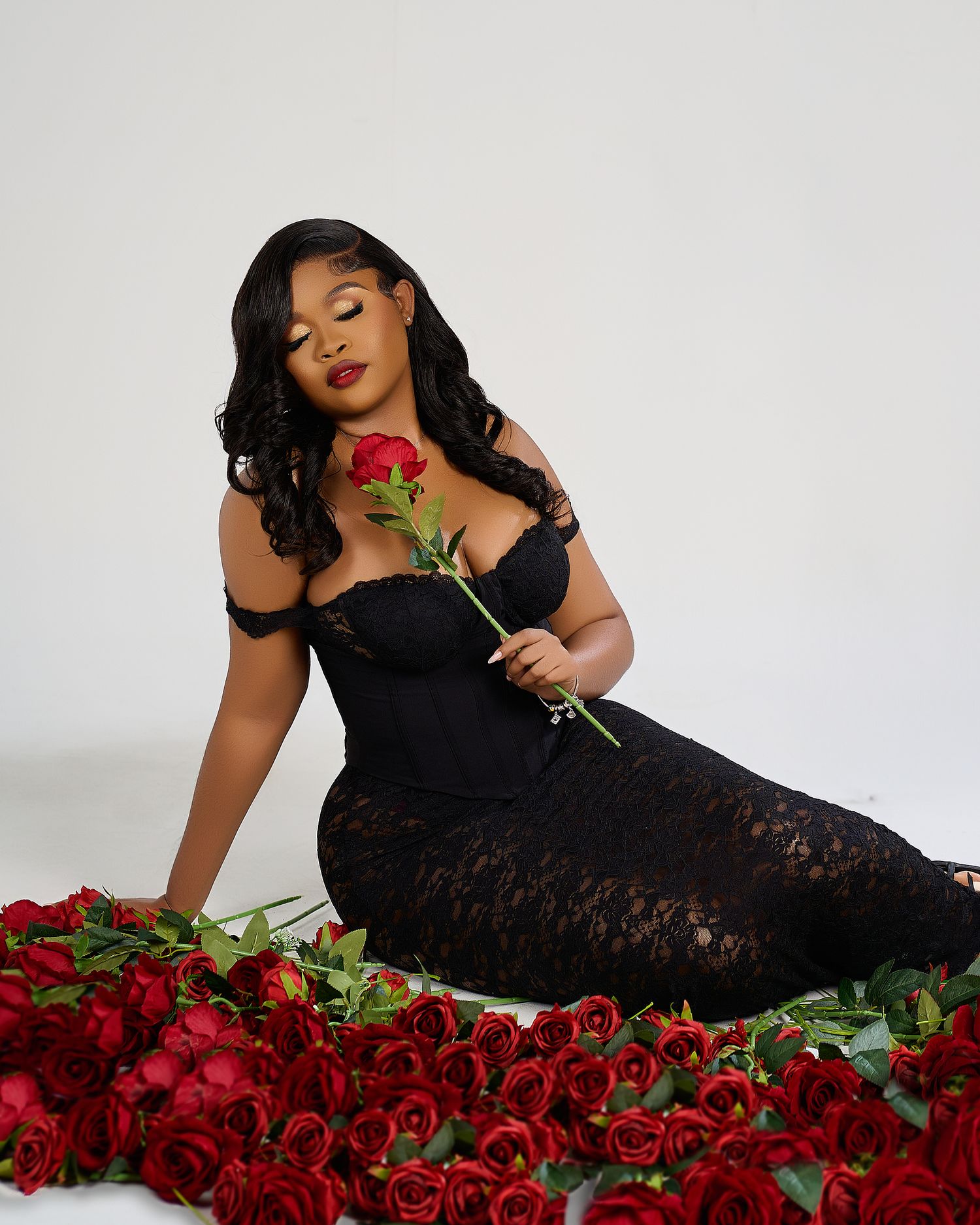 Elegant portrait with model in black lace dress posing with red roses.