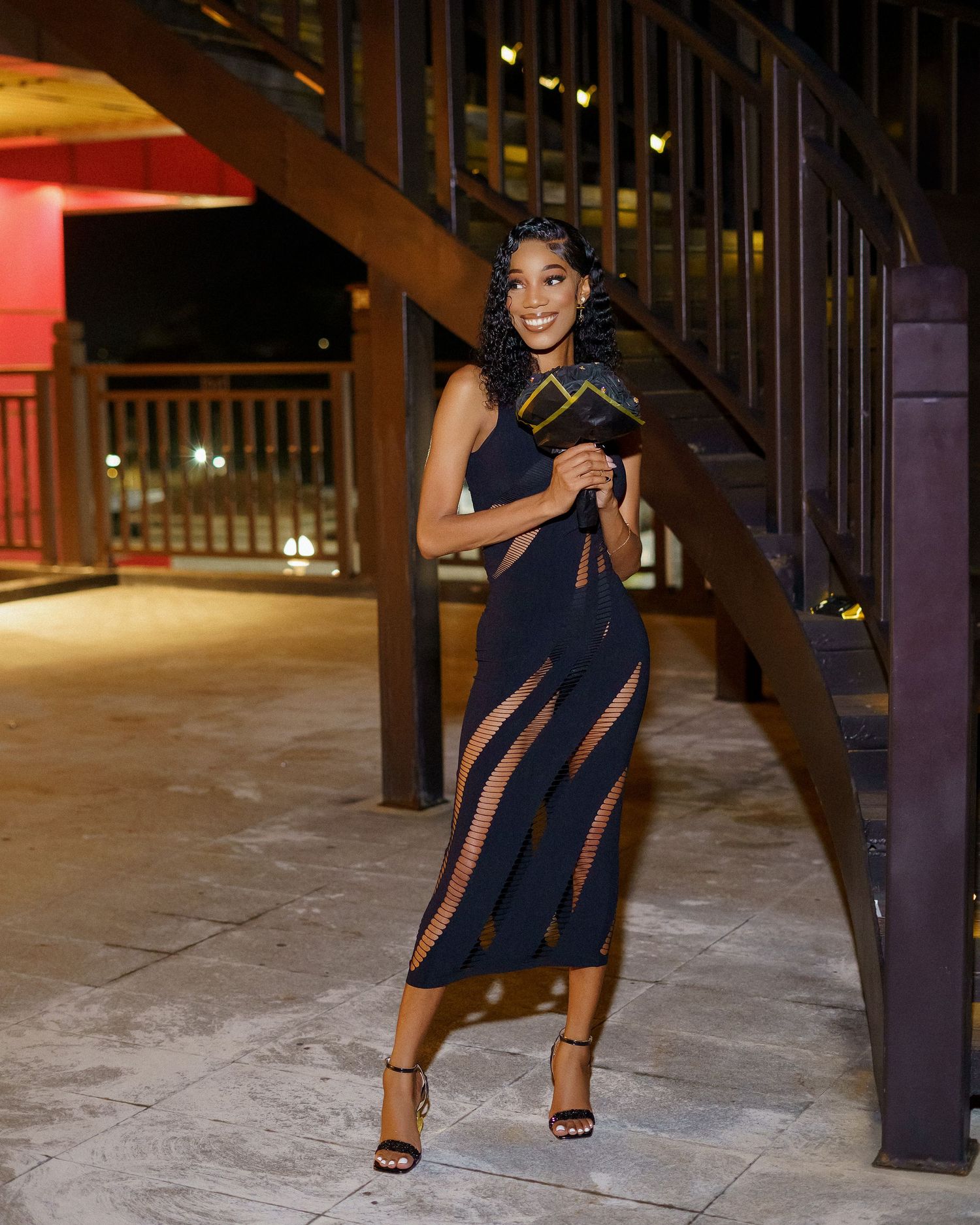 Evening fashion shoot featuring a navy dress with sheer panels in an urban architectural setting.