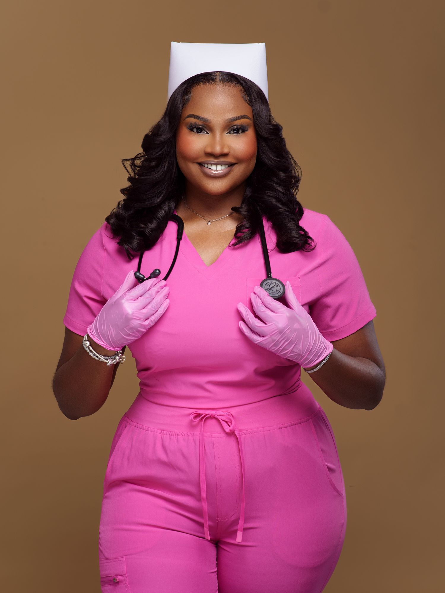 Fashion portrait series in bright pink jumpsuit and gloves against brown backdrop.