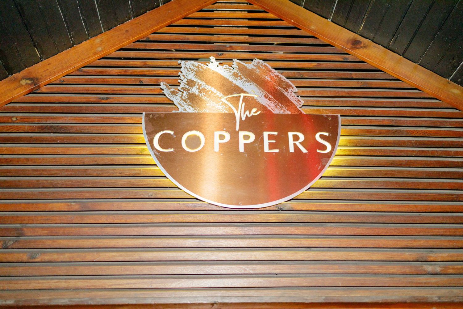 Illuminated wooden wall with Coppers signage in modern restaurant setting.