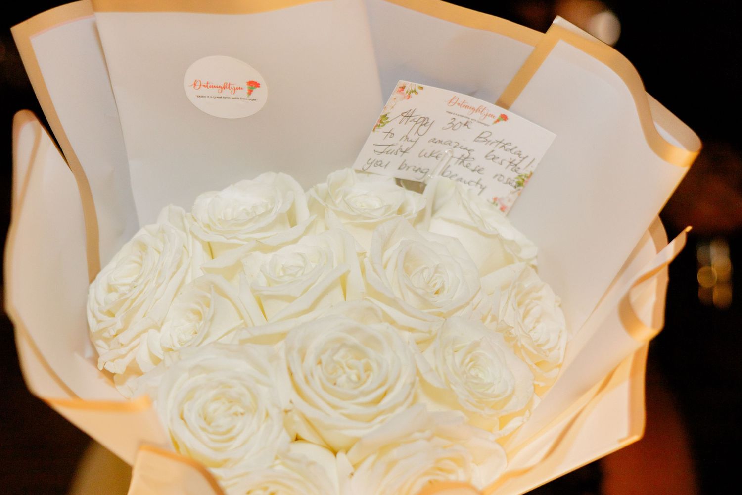 Elegant white roses arranged in a bouquet against dark background.