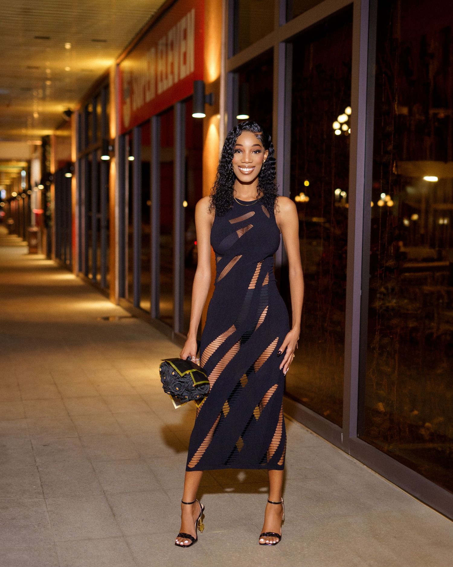 Fashion model poses in stylish navy dress against urban nighttime backdrop.