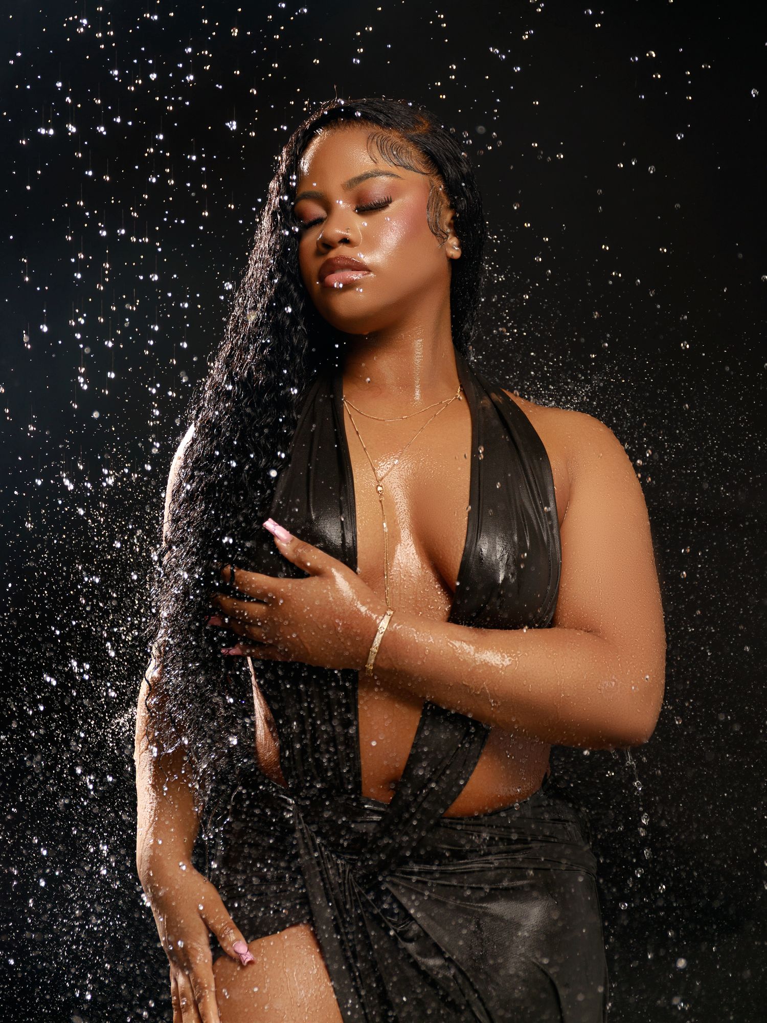 Fashion photo with water droplets featuring model in black halter top.