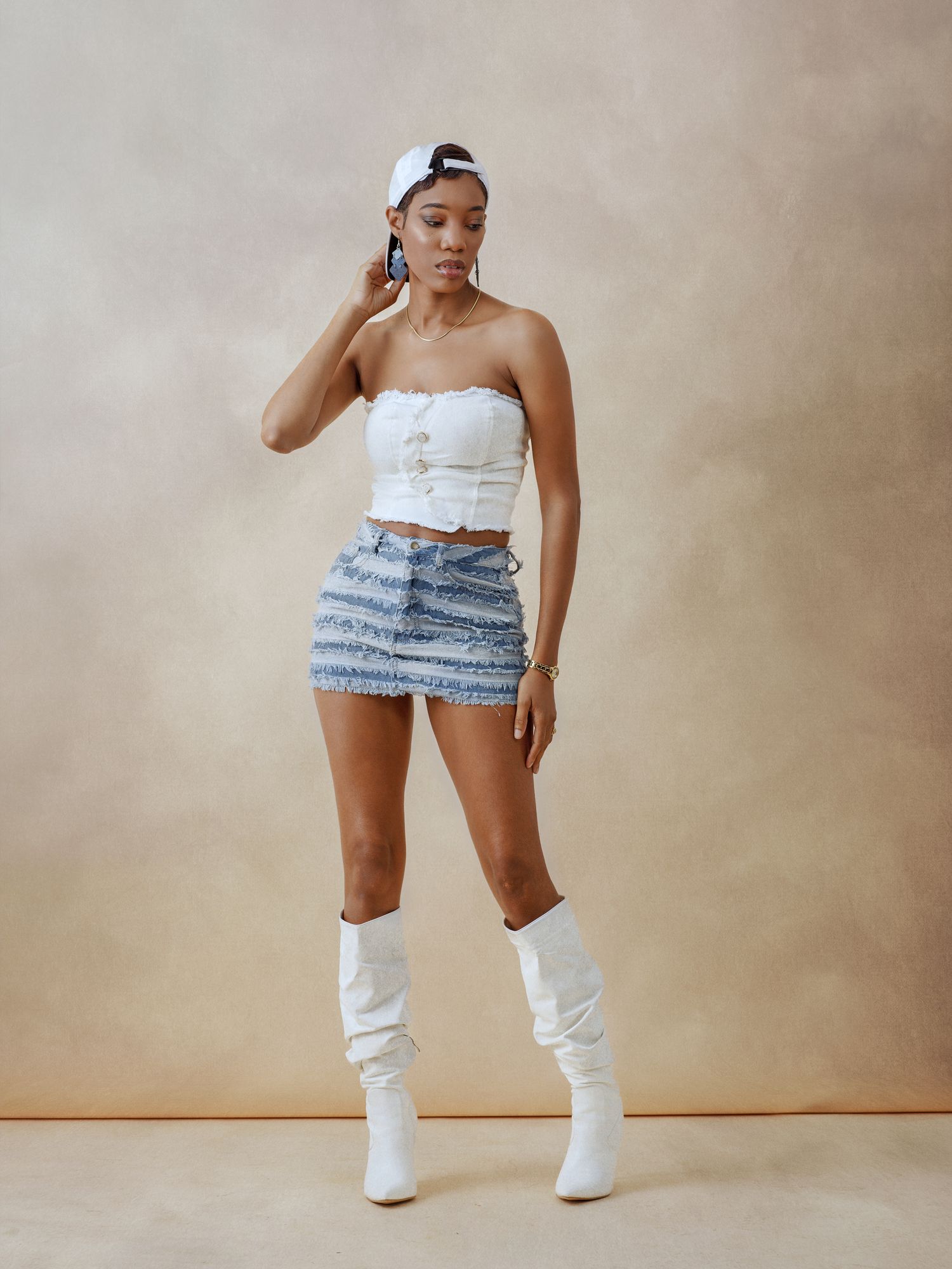 Fashion photoshoot featuring white boots and denim outfit against neutral background.