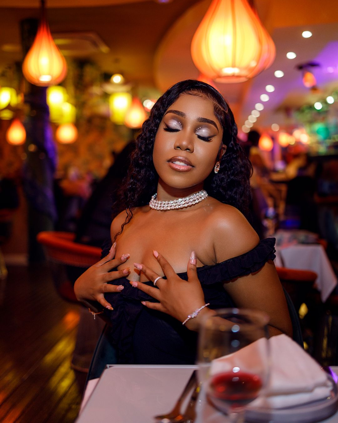 Glamorous portrait in a restaurant with warm lighting and colorful paper lanterns creating ambiance.