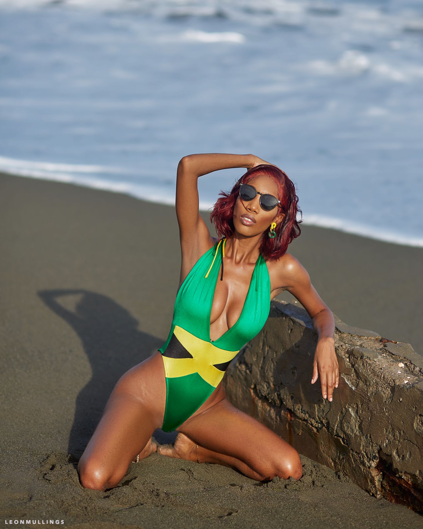 Artistic beach poses with driftwood featuring green and yellow swimsuit design.
