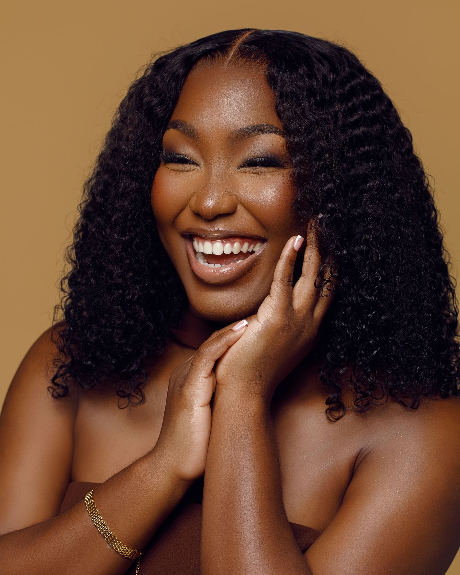 Beauty portraits with natural curls against warm golden background.