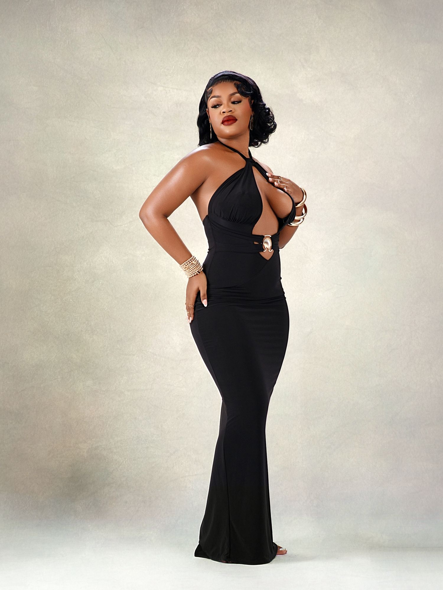 Elegant black evening gown photo session against neutral studio backdrop.