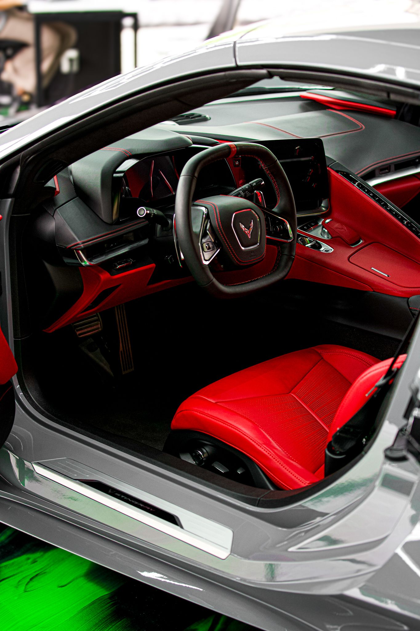 Corvette interior featuring red leather seats, black dashboard, and sporty steering wheel with red accents.