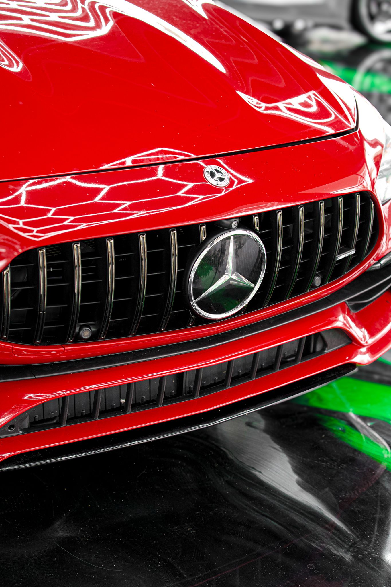 Close-up of a red Mercedes-Benz sports car front grille with iconic three-pointed star logo.
