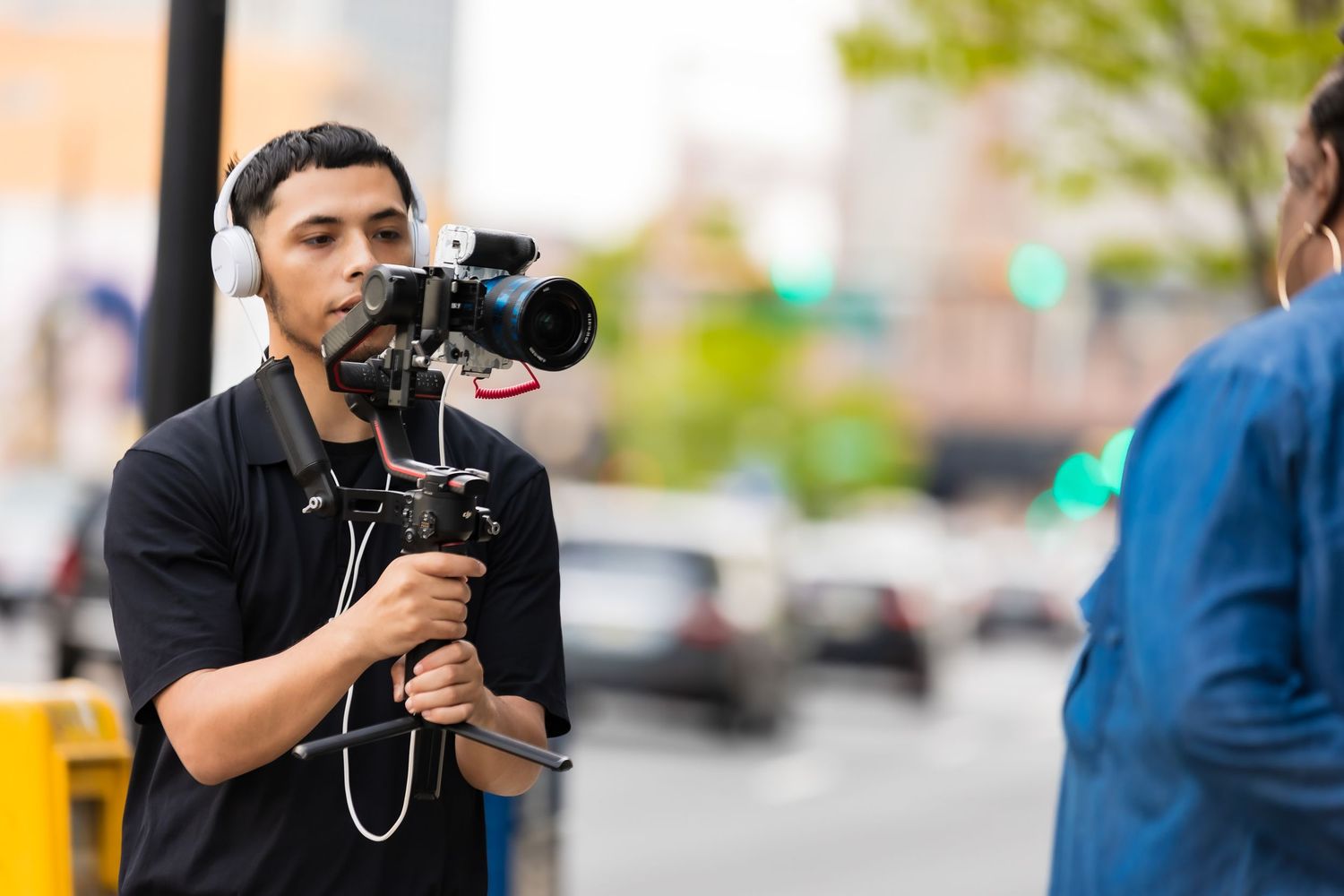 Videographer filming with professional camera equipment on city street.