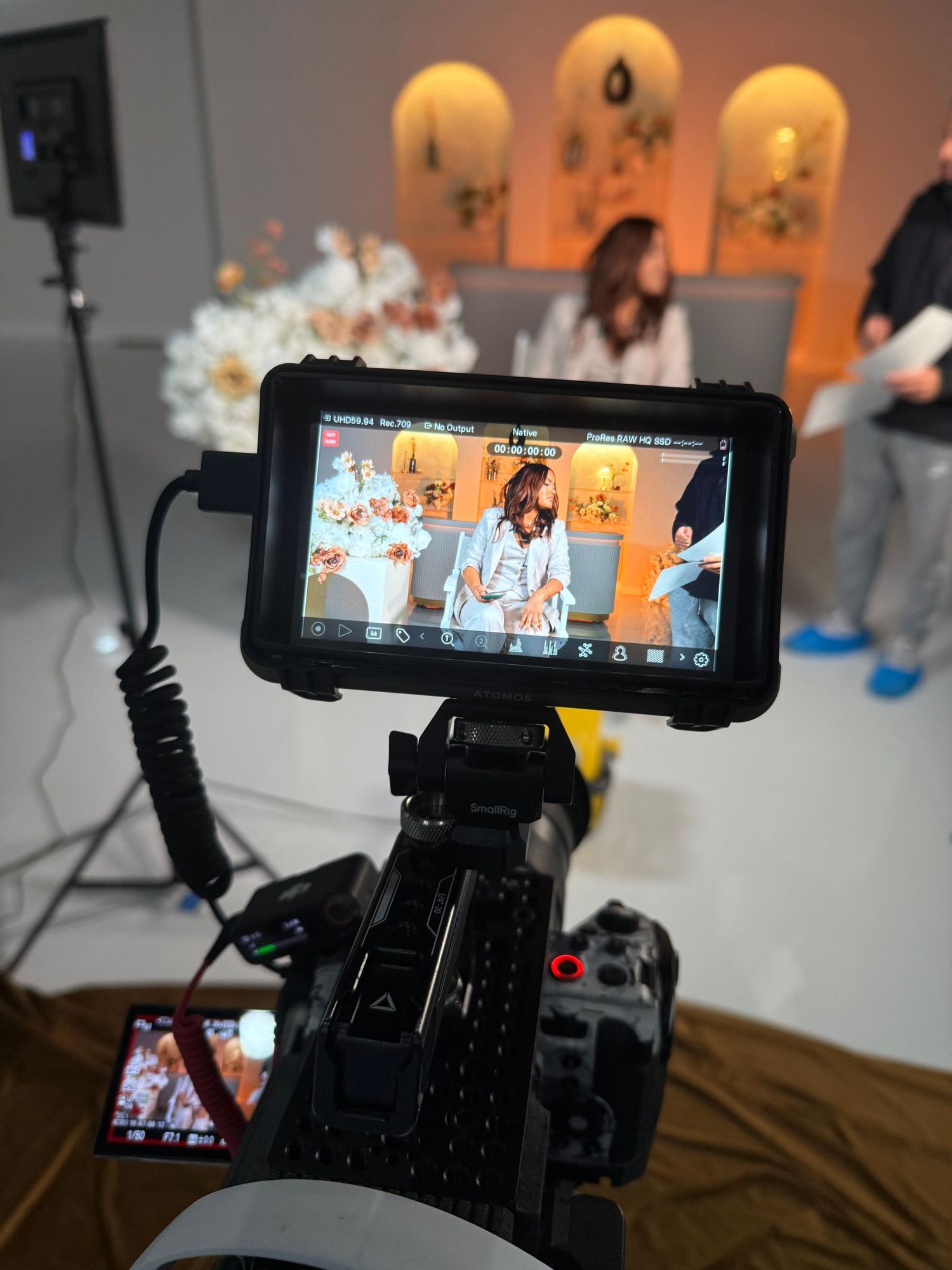 Camera monitor display showing live video feed in a studio with decorative arched panels.