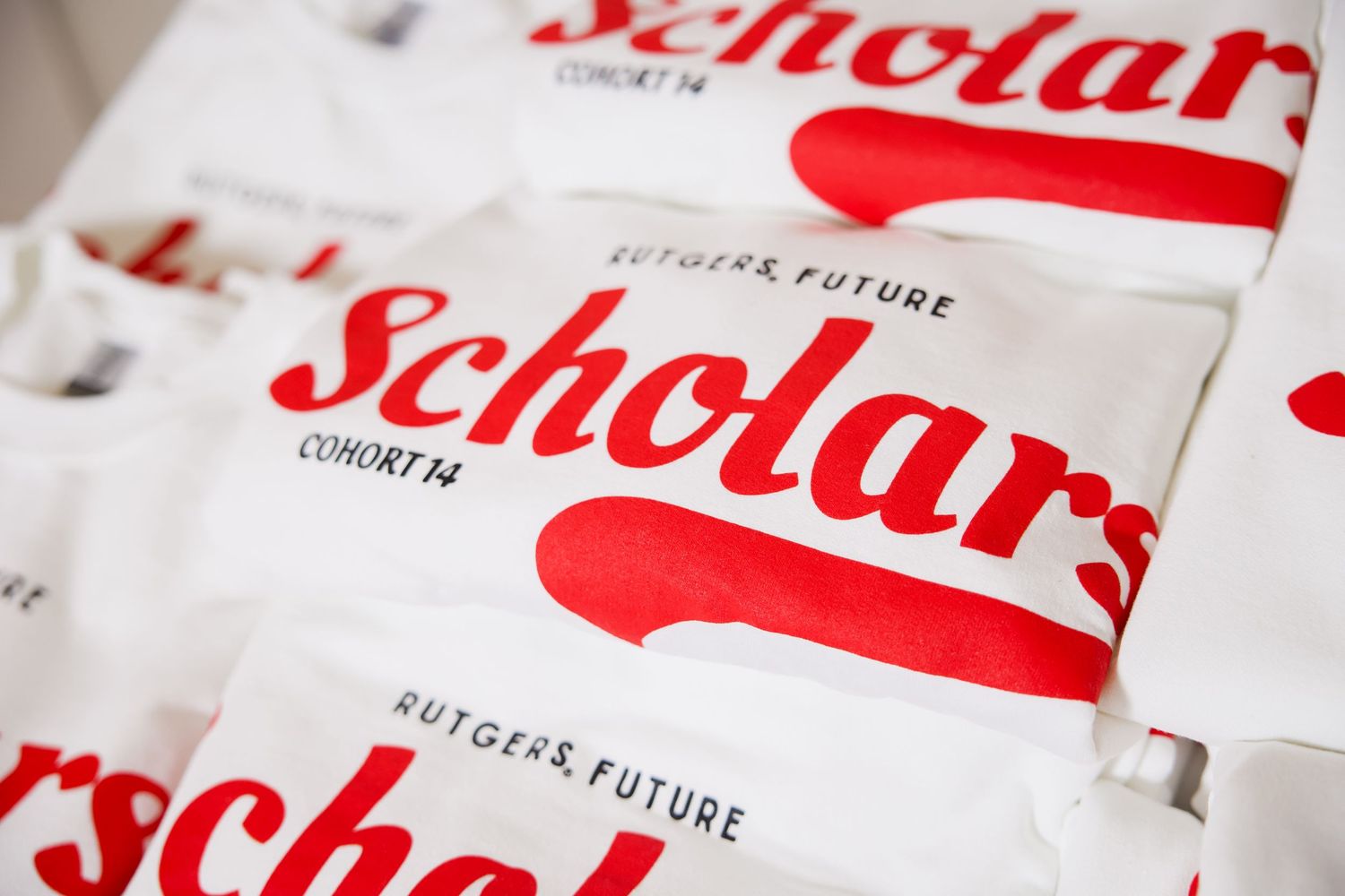 Stack of white tote bags printed with Rutgers Future Scholars Cohort 14 logo in red and white.