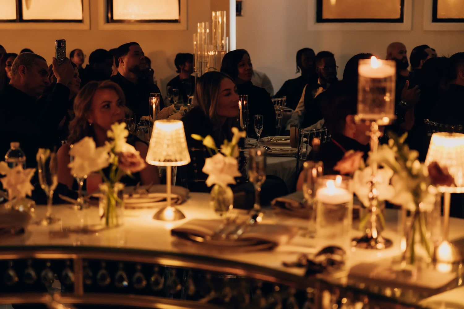 Elegant table setting with candlelight and floral arrangements at an evening event.