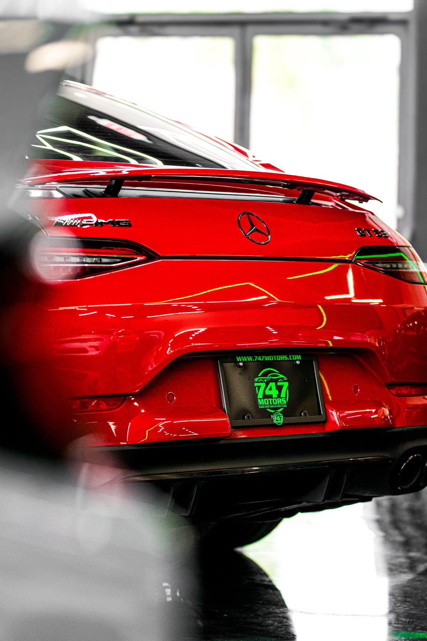 Red Mercedes-AMG GLE Coupe rear view with 747 Motors dealer plate in a showroom.