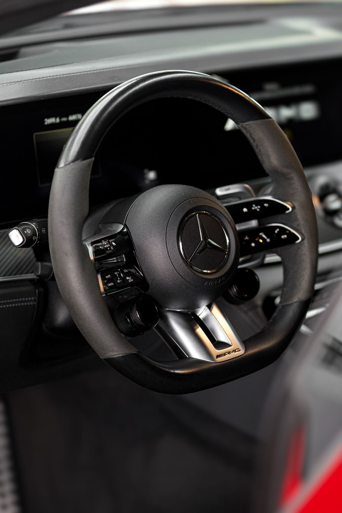 Black Mercedes-AMG flat-bottom steering wheel with gold accents and carbon fiber trim in a luxury sports car interior.