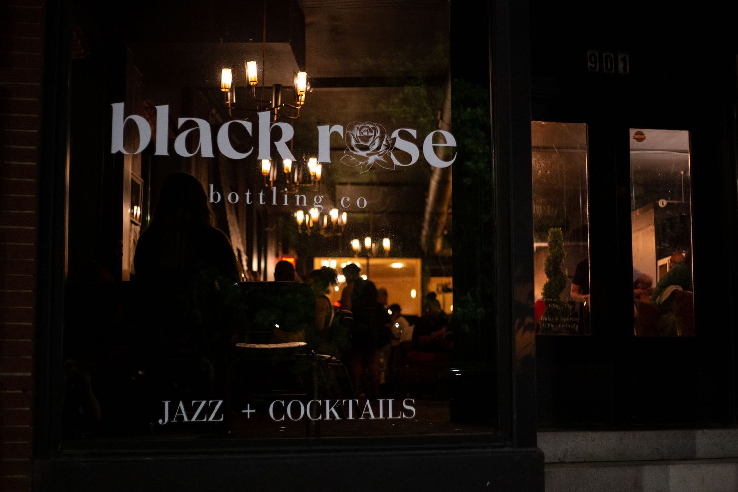 Black Rose Bottling Co. jazz and cocktails bar storefront illuminated at night with warm interior lighting.