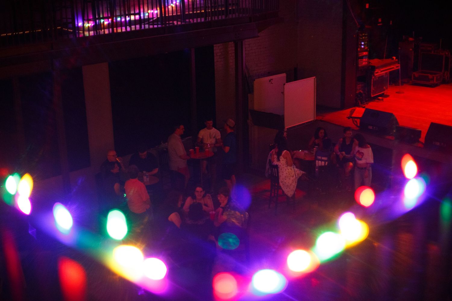 Colorful LED lights circle a dimly lit event venue with guests mingling on the dance floor.